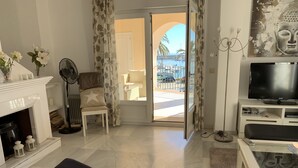 Un salon avec une cheminée, un téléviseur, un canapé et une vue sur l’extérieur.
