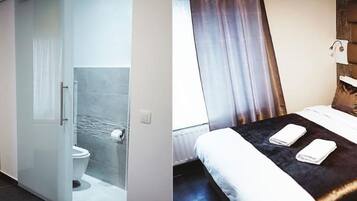Une chambre d’hôtel équipée d’une douche, de toilettes et d’un lit avec des oreillers et une couverture.