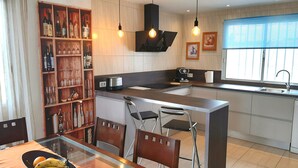 A modern kitchen with a central island, wooden wine rack, and pendant lighting.