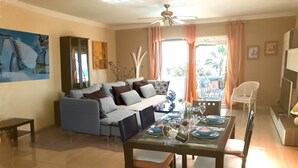 A dining area with a glass table set for four, surrounded by wooden chairs.