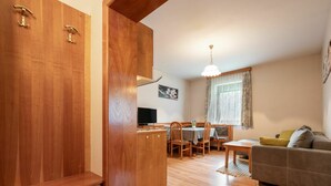 Un espace de vie compact comprenant une armoire en bois, un coin repas avec un téléviseur et un canapé.