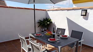 A patio with a table set for two, featuring a bottle of wine, glasses, and plates of food. - Beautiful and sunny house in Cordoba (Córdoba)