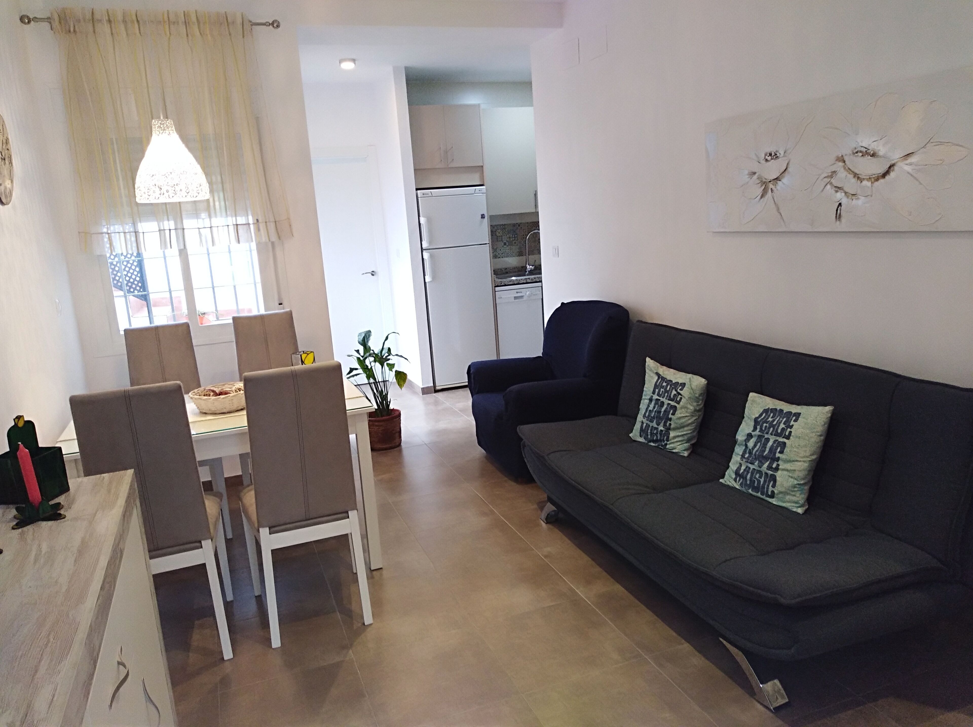 Un salon moderne avec un canapé, des fauteuils, une table à manger et une cuisine en arrière-plan.