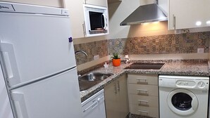 A compact kitchen with a refrigerator, microwave, sink, and washing machine. - Beautiful and sunny house in Cordoba (Córdoba)