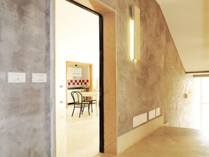 A modern interior with a kitchen area, a dining table with chairs, and a large open space with a high ceiling.