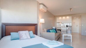 Habitación de hotel con una cama grande, un sofá, una mesita y una kitchenette.