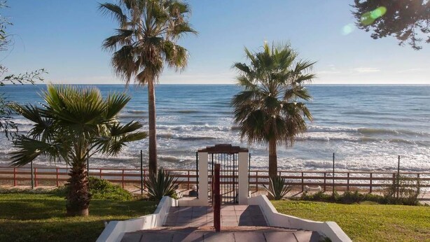 Vista de la playa con palmeras y una entrada cerrada.