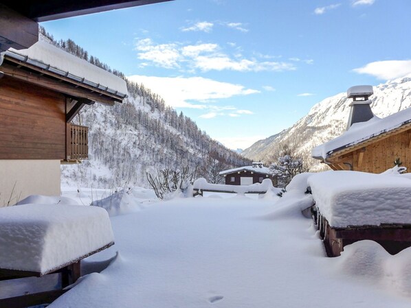 A snow-covered wooden building with a clear view of a mountainous landscape.