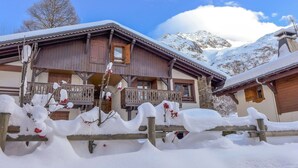 Een houten chalet met balkon, omringd door met sneeuw bedekte bomen en bergen.