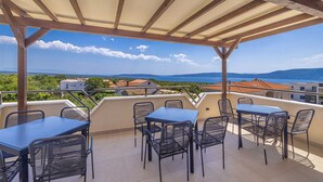 A covered outdoor seating area with tables and chairs, overlooking a scenic landscape with buildings and a body of water. - Villa Haya - apartment KAMELIJA with heated pool (Linardići)