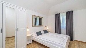 A bedroom with a bed, a wardrobe, a mirror, a nightstand, and a window with curtains. - Villa Haya - apartment KAMELIJA with heated pool (Linardići)