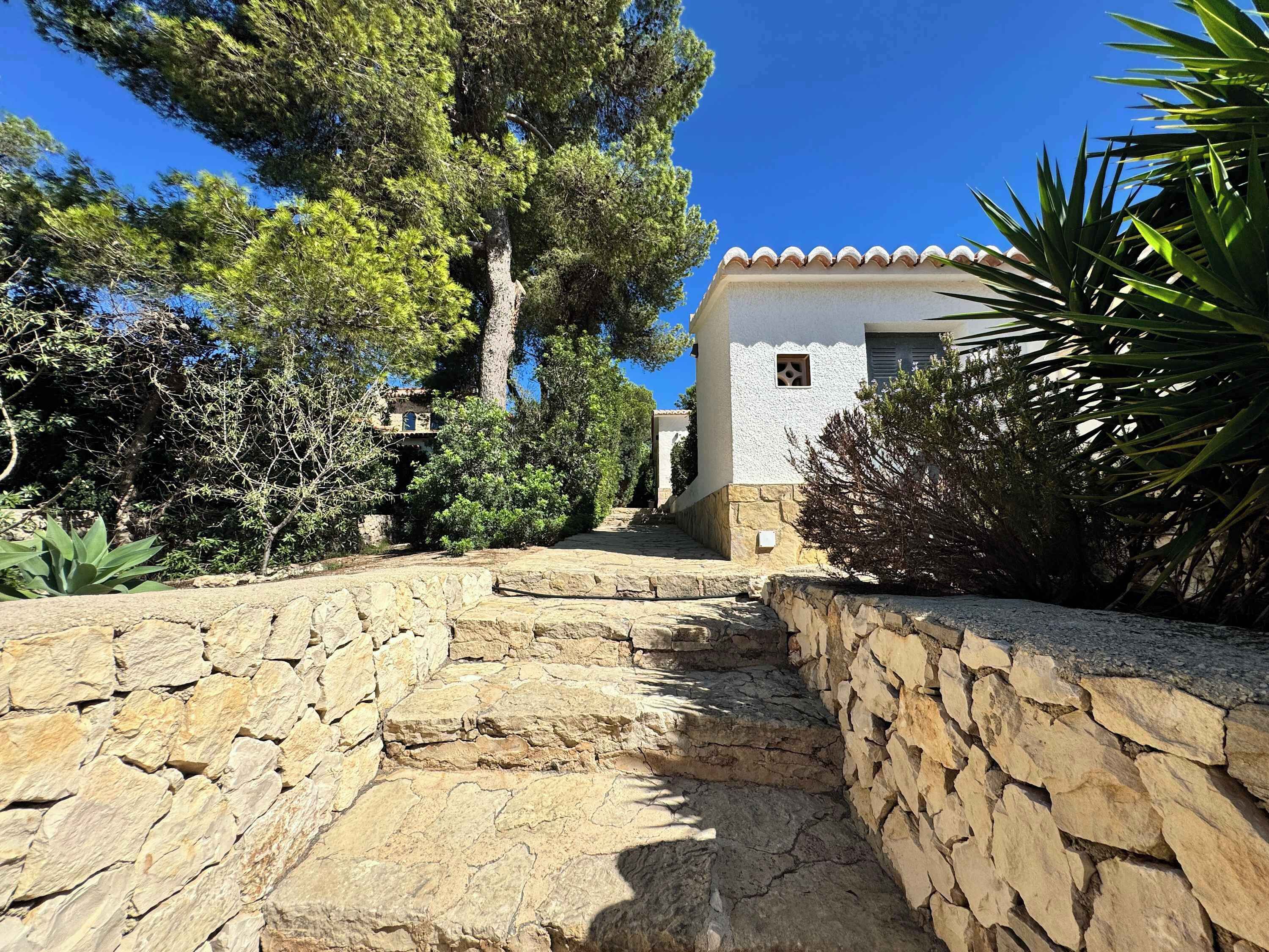 A stone staircase leading to a building with a white facade and a tiled roof.