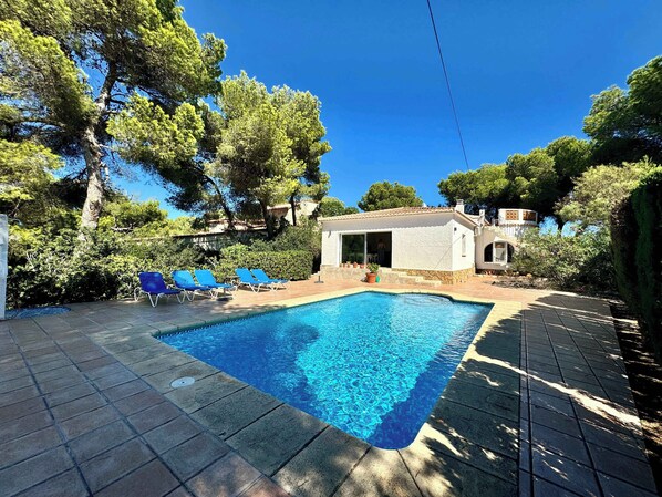 A swimming pool with blue water, surrounded by a tiled deck and blue lounge chairs. - Wonderful holiday villa with private pool, air condition (Xàbia)