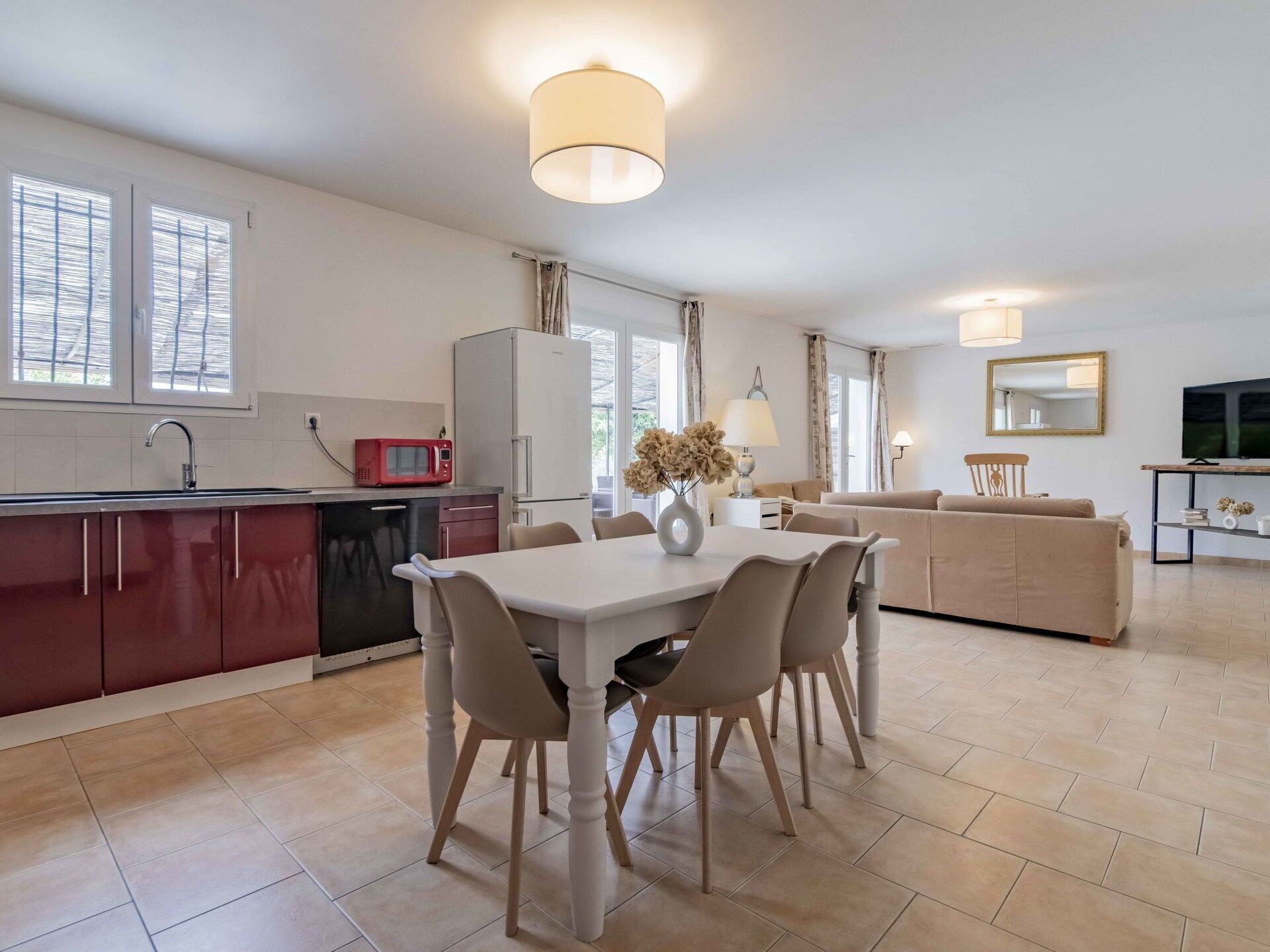 A modern kitchen with a dining area, a sofa, and a TV.