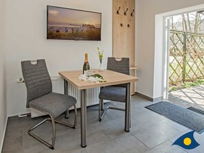 Un comedor con una mesa, dos sillas, una botella de champán y un cuadro en la pared.