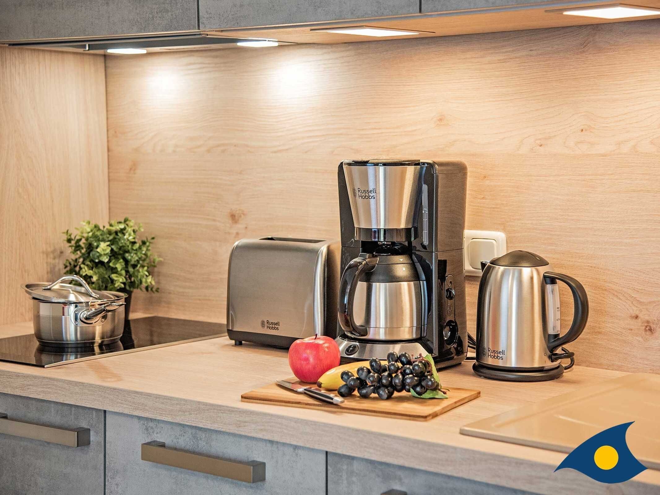 Una cocina moderna con cafetera, tostadora, hervidor y una olla sobre la encimera.