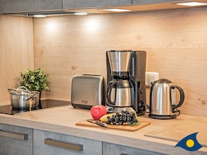 A modern kitchen with a coffee maker, toaster, kettle, and a pot on the counter. - Eichelhäher Vacation Home - A Retreat with a Grill & Terrace - Eichelhäher (Heringsdorf)