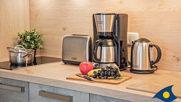 Una cocina moderna con cafetera, tostadora, hervidor y una olla sobre la encimera.