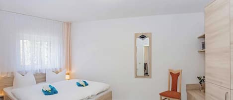 Une chambre à coucher avec un lit, une chaise, une armoire et un miroir.