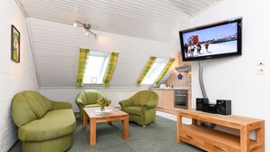 A modern living room with a sofa, a coffee table, a TV, and a wooden TV stand. - Apartment "Seediek" - Farm on the dike (Esens)