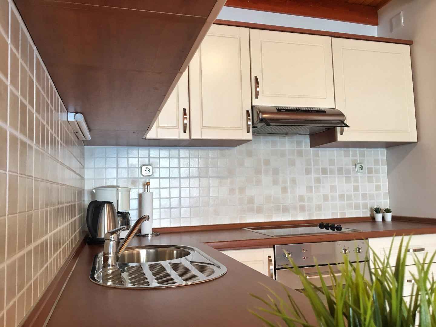 A kitchen with white cabinets, a stainless steel sink, and a modern stove.