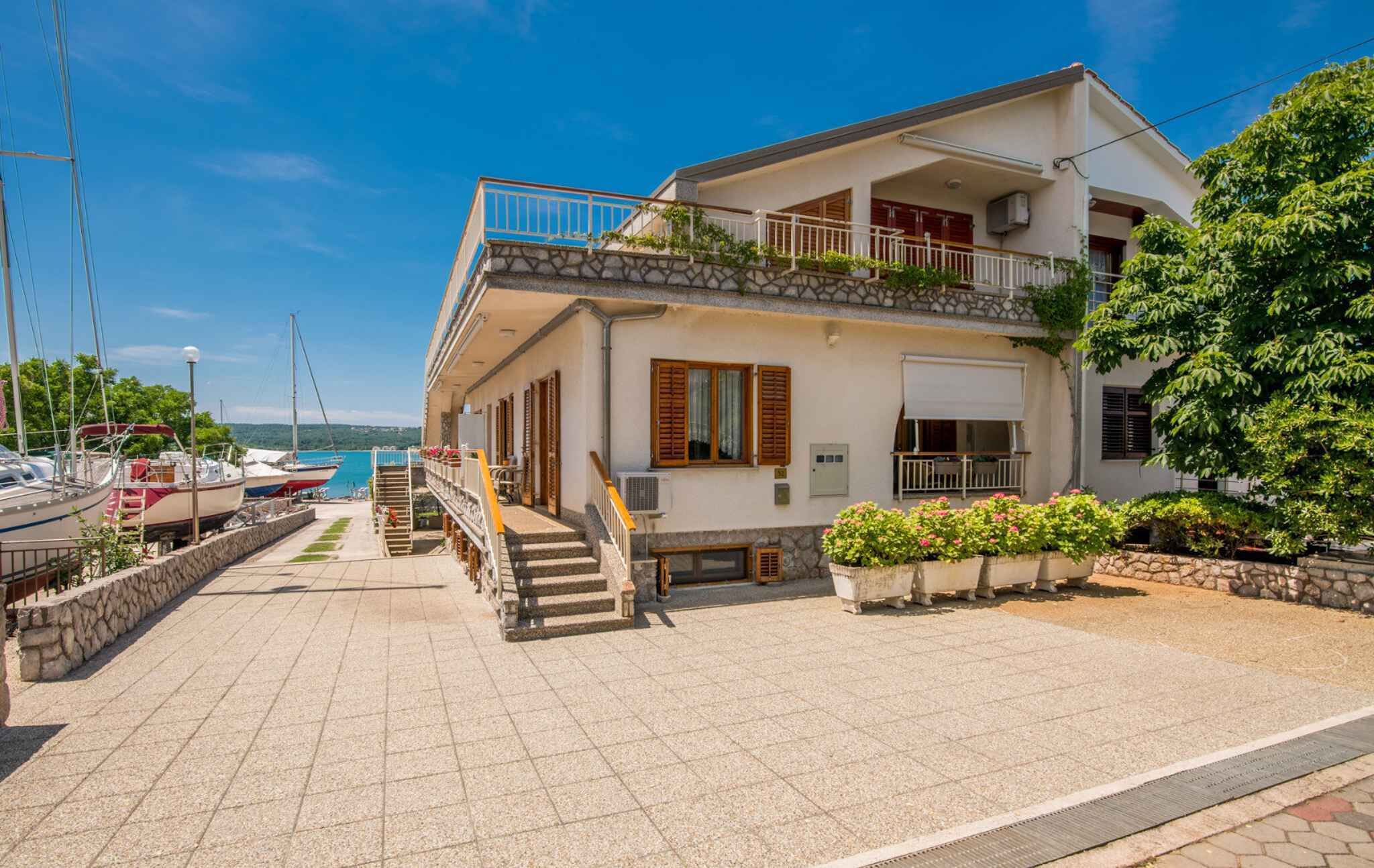 Ein zweistöckiges Haus mit einem Balkon, einer Steintreppe und Blick aufs Meer.