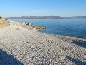 Enjoy a serene beach experience with a clear view of the sea and distant hills.