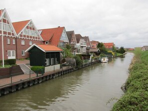 A canal lined with traditional houses, a small boat docked on the water, and a pedestrian bridge.