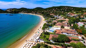 Une ville côtière dotée d’une plage, de maisons aux toits recouverts de tuiles rouges et d’une mer d’un bleu limpide.