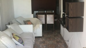Un salon moderne avec un canapé blanc, une petite table et un téléviseur fixé au mur.