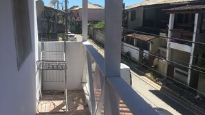 Un balcon doté d’un sol carrelé, d’une rambarde en métal et offrant une vue sur les bâtiments voisins.
