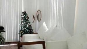 Un salon avec un canapé blanc, une table basse, un petit sapin de Noël et un tapis à motifs.