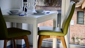 Une table à manger avec deux chaises, une bouteille de vin et deux verres.
