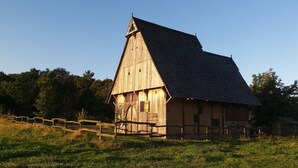 A wooden barn with a sloped roof, surrounded by a wooden fence and a grassy field. - Cozy holiday apartment, surrounded by wood and grassland, chimney, pets allowed (Niedersachsen)