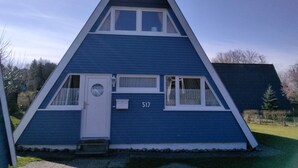 A blue, triangular-shaped building with a white door and windows, marked with the number 517. - Sunny, cozy wooden holiday house with big terrace and BBQ (Schleswig-Holstein)