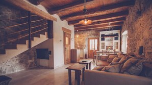 A rustic interior with a stone staircase, a wooden ceiling, a sofa, and a dining area with a view of the outdoors. - Luxury Villa DELUXE with pool and sauna (Gabonjin)