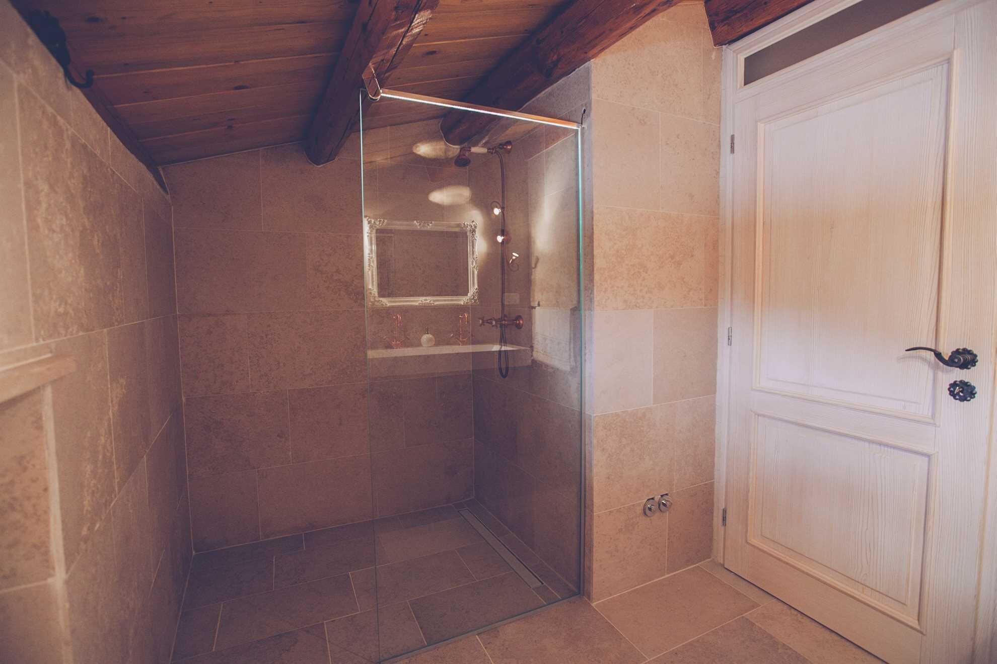 A bathroom with a glass shower enclosure, a white door, and tiled walls.