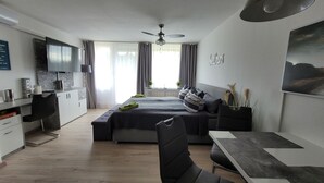 Een moderne hotelkamer met een bed, een bureau, een stoel, een televisie en een plafondventilator.