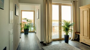 A spacious hallway with wooden flooring, large windows with curtains, and potted plants. - Apartment in an idyllic location and great views (Dormettingen)