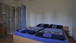 A bedroom with a bed, a shower, and a small wooden cabinet. - Ground floor apartment (Neukirch)