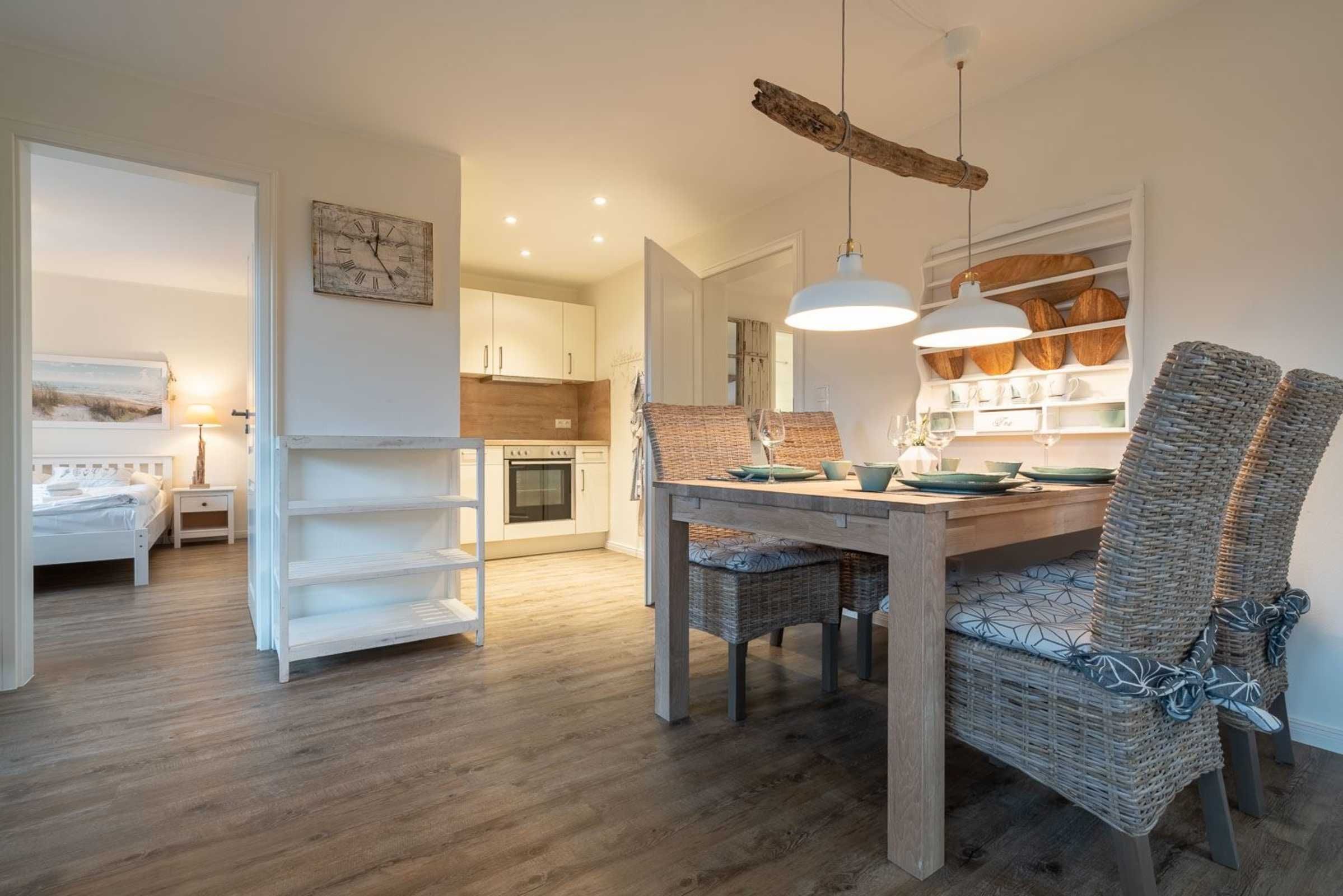 Un coin repas chaleureux avec des chaises en osier, une table en bois et des lampes suspendues.