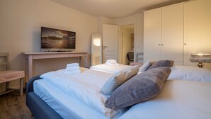 A hotel room with a bed, a television on a stand, a desk, and a wardrobe.