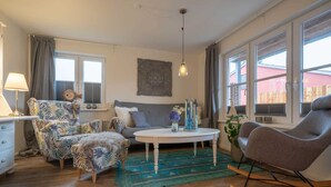 A cozy living room with a sofa, armchair, ottoman, and a round coffee table.