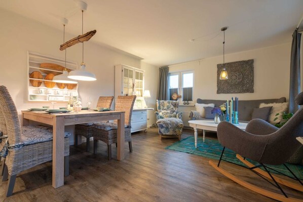 Un salón acogedor con comedor, con muebles de mimbre, una mesa de madera y un sillón mecedor.