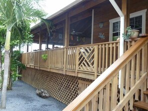 A wooden deck with a wooden railing, a rock, and a potted plant.