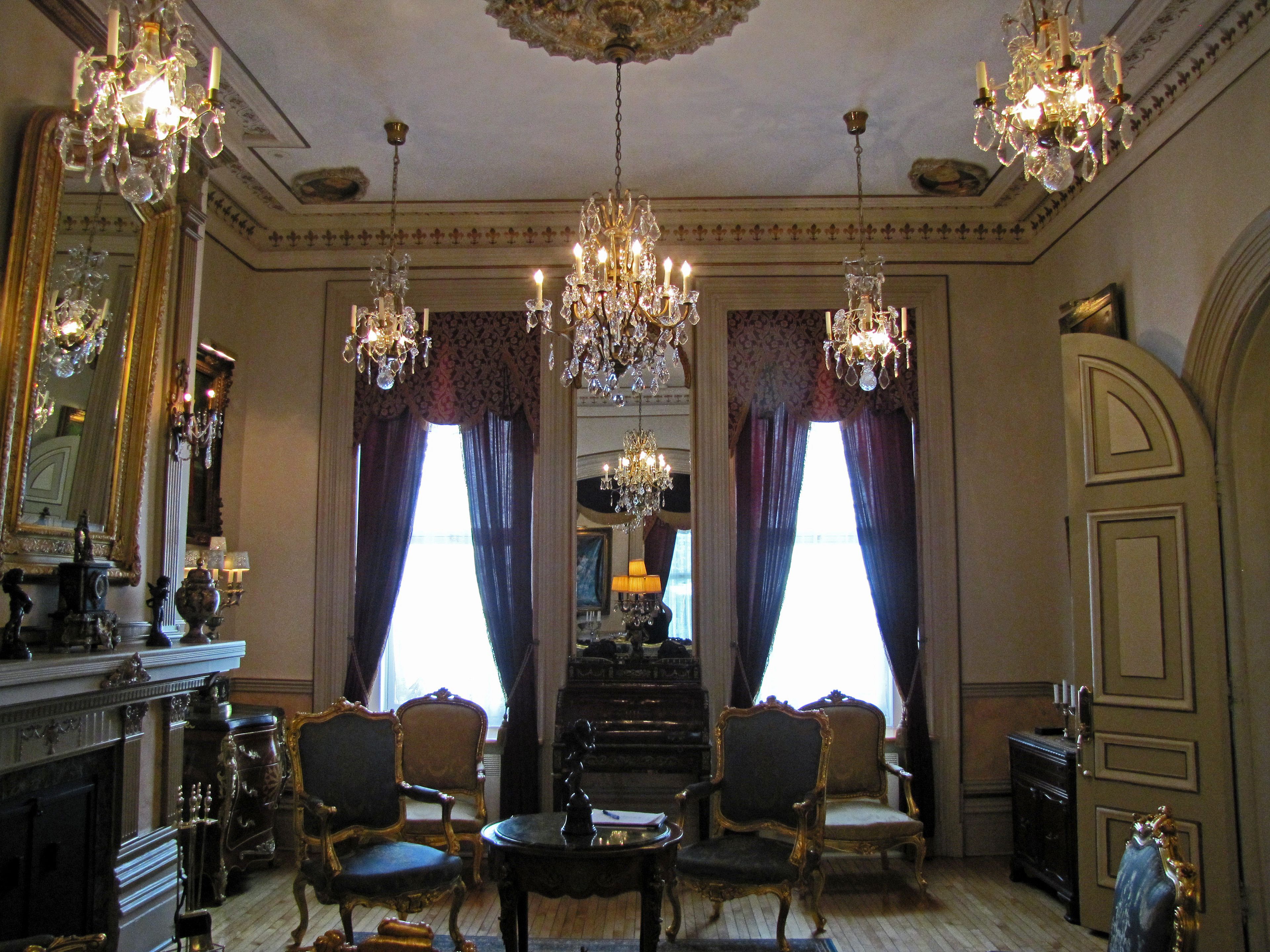 Une pièce agrémentée de lustres décoratifs, d’une cheminée et de meubles de style classique.