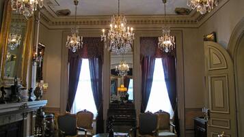 Une pièce agrémentée de lustres décoratifs, d’une cheminée et de meubles de style classique.