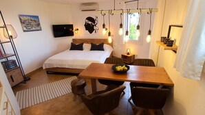 Ein Schlafzimmer mit Bett, Nachttisch und Schreibtisch. Es gibt einen Essbereich mit Tisch und Stühlen.
