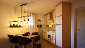 Eine kleine Küche mit Essbereich, Holzschränken und einer Pendelleuchte.