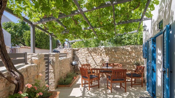 A covered outdoor seating area with stone walls and a pergola, featuring a table and chairs. - Holiday home With terrace and whirlpool (Medulin)